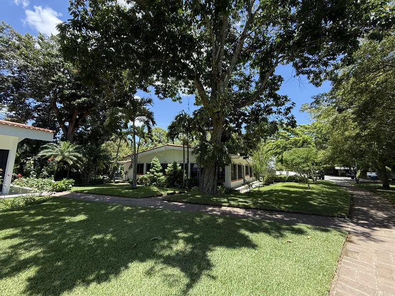 Jardín con árboles grandes y la capilla de la Parroquia Nuestra Señora de las Gracias, Onuva